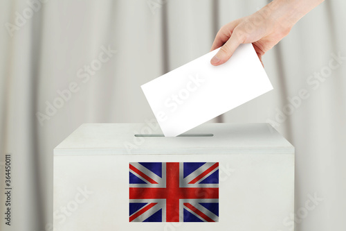 UK Vote concept. Voter hand holding ballot paper for election vote on polling station