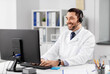 © Syda Productions - healthcare, medicine and technology concept - happy smiling male doctor with computer and headset working at hospital