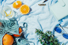 Summer Picnic Flatlay Of Fruits, Flowers And Lemon Water On A Blue Blanket