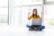© dianagrytsku - Happy asian woman using laptop while sitting on floor in living room.