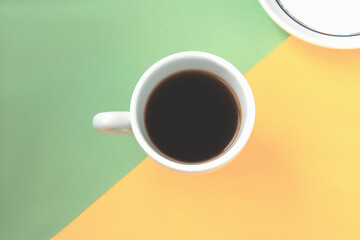 Black coffee in a white cup on green and yellow background