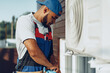 © fotofabrika - Young black man repairman checking an outside air conditioner unit