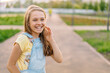 © KseniaJoyg - Portrait of a laughing little girl child 9-12 years old in a denim jumpsuit on the street on a Sunny day