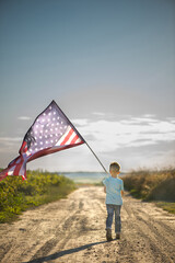 Child is holding American flag, back view.