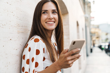 Wall Mural - Image of happy brunette woman smiling and using mobile phone