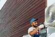© fotofabrika - Repairman in uniform installing the outside unit of air conditioner