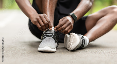 Cuadros en Lienzo Closeup of black sportsman tying his shoelaces before training