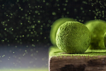 Homemade truffle sweets with matcha green tea on a dark background. Raw energy balls.