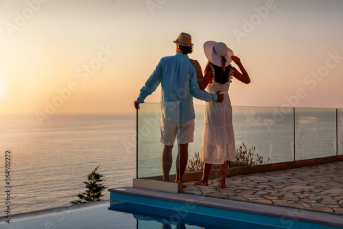 Cuadros en Lienzo Romantisches Paar im Sommerurlaub steht am Pool und genießt den Sonnenuntergang