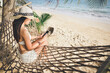 © Peera - Traveler asian woman with mobile phone relax in hammock on summer beach Thailand