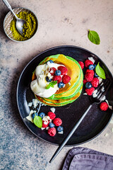 Poster - Matcha tea pancakes with berries, dark background, top view. Healthy vegan food concept.