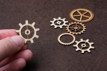 Sticker - Soft focus of a hand holding a wooden gear against a  blurry background