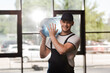 © LIGHTFIELD STUDIOS - happy delivery man in uniform holding bottled water