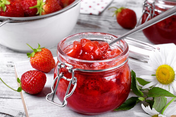 Wall Mural - Strawberry jam in glass jar on the white wooden table. Berries around