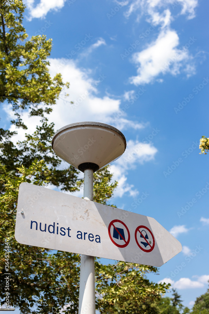 Information sign indicating designated area for nude sunbathing. Nudist area indication in beach