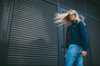 © BullRun - Portrait of cheerful stylish woman with gorgeous blonde hair smiling at camera while standing on promotional background.Positive hipster girl in eyewear dressed in denim apparel near copy space area
