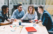 © BullRun - Multicultural group of male and female professionals dressed in formal wear discussing own internet website during briefing in office.Diverse young people collaborating on business project