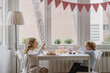 © Angel Santamaria/ADDICTIVE STOCK - Side view of cheerful little kids in casual clothes sitting at wooden table near window and eating sweet cake during holiday