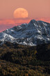 © Juan Lopez/ADDICTIVE STOCK - Majestic mountain landscape with full moon in colorful sky over snowy rocky range and dense forest in autumn time