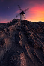 Aged Windmill Located On A Rocky Cliff Against Cloudy Sundown Sky In Countryside