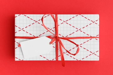 Sticker - White christmas gift with a blank tag mockup on a red background.