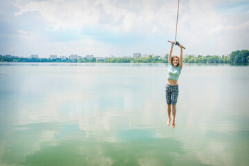 In the summer, on a bright sunny day, children ride a bungee on the lake.