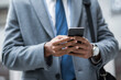 © Widetape/ADDICTIVE STOCK - Faceless shot of black businessman in suit and watch using smartphone outside.