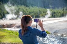 Woman Taking Pictures Of Firehole River In Yellowstone National Park