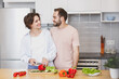 © ViDi Studio - Smiling young couple friends guy girl in casual clothes preparing vegetable salad cooking food in kitchen at home. Dieting family healthy lifestyle concept. Mock up copy space. Looking at each other.