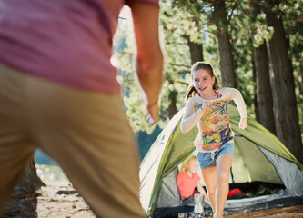 Wall Mural - Daughter running to father outside tent in woods