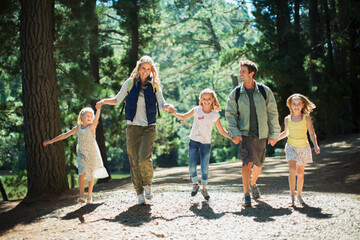 Wall Mural - Smiling family holding hands and walking in woods