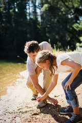 Wall Mural - Father and daughter gathering stones on beach at lakeside