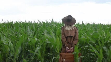 Sticker - Blonde woman in cloak and hat with suitcase in cornfield in summertime