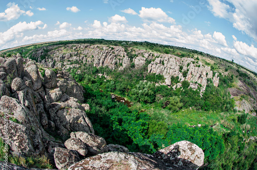 Stone gray canyon among green trees, river between the mountain. One of the Wonders of the World of Ukraine is the Act of Devil\'s Canyon. Traveling around the country by car, climbing, climbing