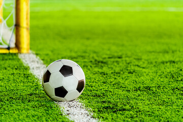 classic black and white football soccer ball on training pitch goal line with goal in the background