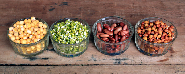 Wall Mural - Collection of legumes (chickpeas, green peas, green mung beans, Red Kidney, Dry peas)in different bowls isolated on wooden background.