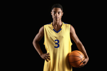 Young African-American basketball player on dark background