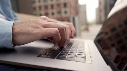 a man types on a laptop keyboard a message and surfs the space of the internet. working at a compute
