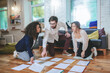 © zinkevych - Serious guy with glasses and two girls laying papers on floor