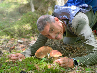 Poster - Satisfied happy man finding two Porcino mushrooms, italian woods