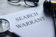 Selective focus of magnifying glass,gavel,glasses and paper written with Search Warrant on white wooden background.