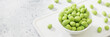 Fried peanuts in wasabi in a white bowl on a light gray table. Banner with space for text	