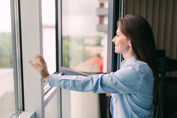 Young woman opening window for fresh air in the morning in living room