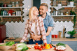© GVS - Smiling young couple cooking together vegetarian meal in the kitchen at home. man embracing woman.