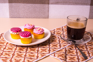 White plate with muffins, cakes, coffee mug on a yellow napkin