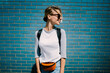 © BullRun - Young positive woman dressed in street style wear looking away standing on blue wall background,smiling hipster girl in trendy casual clothing enjoying leisure outdoors posing on urban settings.