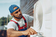 © fotofabrika - Young black man repairman checking an outside air conditioner unit