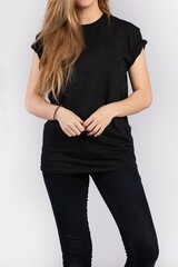 Wall Mural - Young female wearing black short sleeve t-shirt standing against a white wall