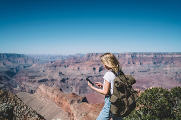 Wall Mural - Young hipster girl checking mail on smartphone hiking in mountains on active weekend,female tourist with backpack using good mobile data connection in wild nature for communicating during tour