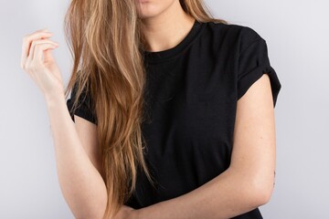 Wall Mural - Young female wearing a black short sleeve t-shirt with a white wall in the background